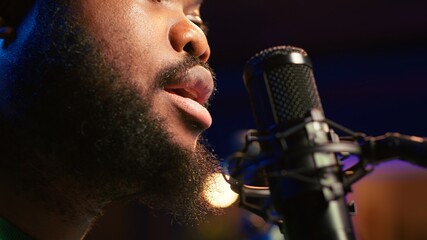 Poster - Artist records his voice on microphone in home studio singing a song composed by him. Skilled musician using recordings and lyrics to edit in post production, mixing and mastering session. Camera A.
