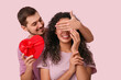 © Pixel-Shot - Young man greeting his beloved girlfriend with Valentine's day on pink background