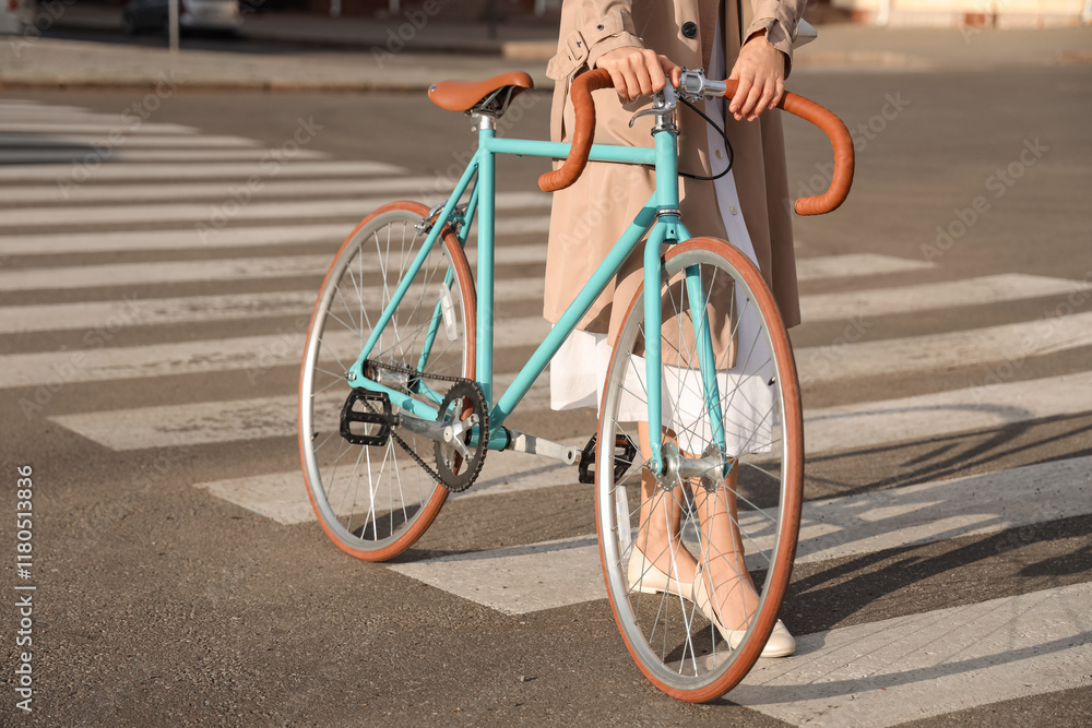 Young woman with bicycle walking across pedestrian crossing