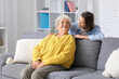 © Pixel-Shot - Young nurse and senior woman sitting on sofa at home