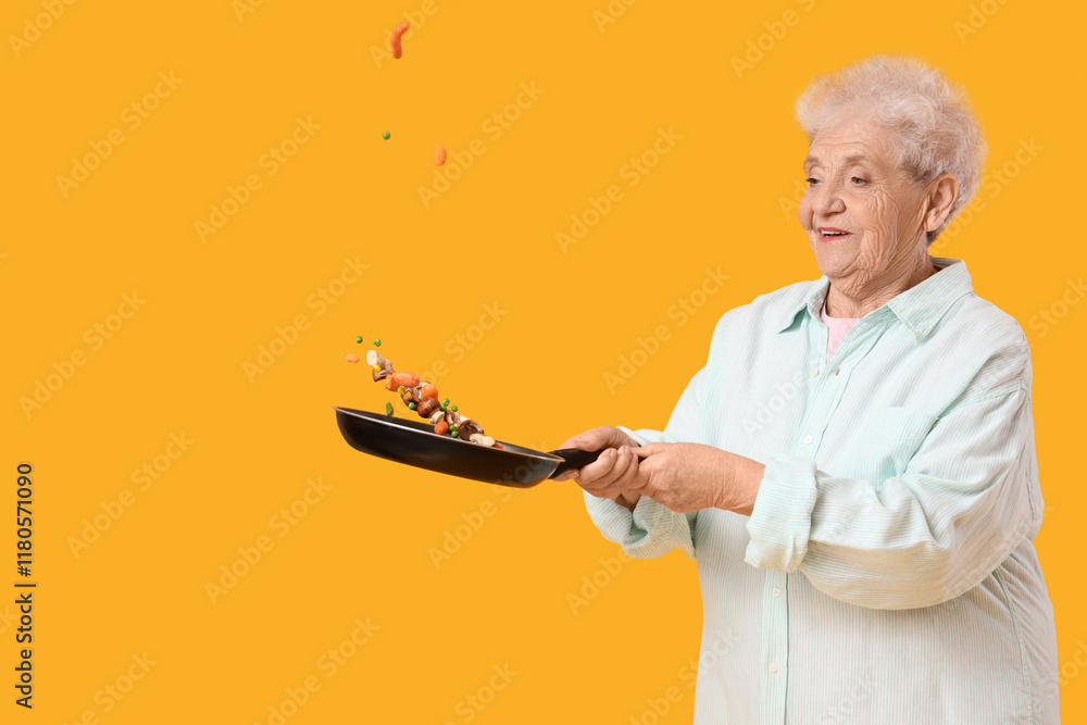 Senior woman frying vegetables on yellow background