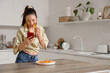 © Pixel-Shot - Young girl with mobile phone eating nachos in kitchen