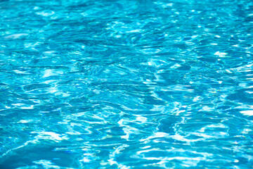 Water background. Blue water, ripples and highlights. Texture of water surface and tiled bottom.