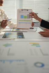 Wall Mural - Businesswomen are discussing savings goals during a meeting, analyzing charts and financial data to track progress and make informed decisions