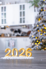 Wall Mural - Golden number 2026 on table in background of cozy white kitchen with Christmas tree and Christmas decor with garland lights. Housing, interior, renovation, mortgage, rent in New Year