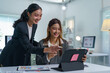 © Phimwilai - Two cheerful asian businesswomen are working together, analyzing data on a tablet and discussing business strategies in a bright, contemporary office environment