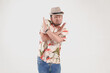 © Reezky - Upset Asian man wearing Hawaiian shirt and hat posing a rejection or stop hand gesture.