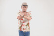 © Reezky - Upset Asian man wearing Hawaiian shirt and hat posing a rejection or stop hand gesture.