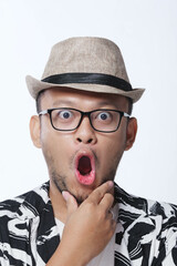 Wall Mural - Close up picture of a shocked young Asian man with his mouth wide open wearing hat and glasses.