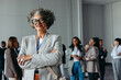© Jacob Lund - Confident mature female professional at a corporate business conference smiling with diverse colleagues in the background
