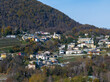 © AmazingAerialAgency - Aerial view of picturesque village with charming houses and peaceful forest in autumn foliage, Bioggio, Switzerland.