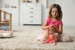 © New Africa - Cute little girl playing with her doll on floor at home. Space for text