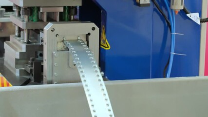 Poster - A machine is cutting a silver strip into small pieces. The strip is being cut into small pieces