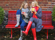 © fStop - Mother and Daughter Sitting on Red Bench with Hot Drinks