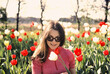 © fStop - Portrait young brunette woman in sunny spring field with red and white tulips