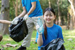 © Natee Meepian - Family volunteer group collecting garbage in a park outdoor environment community effort to clean up