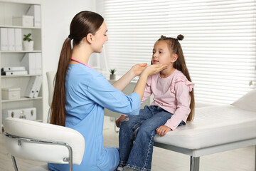 Wall Mural - Doctor examining girl's throat in clinic during appointment