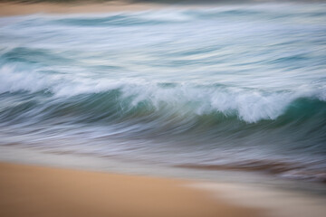 Wall Mural - Small waves break on the beach shore.