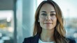 © red_orange_stock - Confident businesswoman stands in a contemporary office, looking directly at the camera with a serene expression in late afternoon light