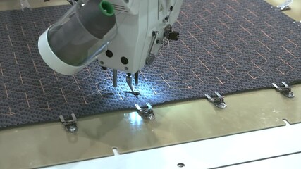 Poster - A sewing machine is in use, stitching a piece of fabric. The machine is bright and shiny, and the fabric is black and white