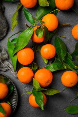 Wall Mural - Tangerines (oranges, clementines, citrus fruits) with green leaves on dark textured background with copy space