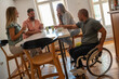 © BalanceFormCreative - Office workers take a coffee break in the company cantina, chatting and laughing around a table.