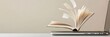© olga_demina - Open book with turning pages over a laptop on a desk with a blank wall in the background, suggesting online education, digital publishing or e learning