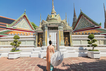 Young asian woman in Thai dress is walking into a beautiful temple.