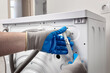 © SKfoto - Plumber in gloves repairing washer on back side. Washing machine repair concept.