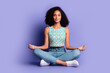 © deagreez - Young woman meditating in trendy summer top against a purple background, showcasing a peaceful lifestyle