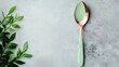 © YURCHENKO ROMAN - A stylish spoon rests beside lush green leaves on stone