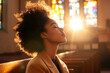 © Anna - A woman sits peacefully in a sunlit church pew, her eyes closed, illuminated by warm rays from colorful stained-glass windows, evoking calm and introspection