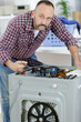 © auremar - working man plumber repairs washing machine in laundry