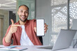 © Liubomir - Man at workplace inside office showing white phone screen to camera, businessman recommending and advertising online financial services app, banking new program.