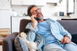 © simona - One adult man alone at home enjoying call communication on smartphone mobile phone device gesturing with hands and smiling happy. Modern people indoor leisure activity. Mature male calling online