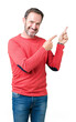 © Krakenimages.com - Handsome middle age hoary senior man wearing winter sweater over isolated background smiling and looking at the camera pointing with two hands and fingers to the side.