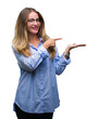 © Krakenimages.com - Young beautiful blonde business woman wearing glasses over isolated background amazed and smiling to the camera while presenting with hand and pointing with finger.