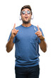 © Krakenimages.com - Young handsome man wearing headphones listening to music over isolated background amazed and surprised looking up and pointing with fingers and raised arms.