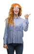 © Krakenimages.com - Young redhead bussines woman smiling with happy face looking and pointing to the side with thumb up.