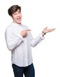© Krakenimages.com - Young handsome business man over isolated background amazed and smiling to the camera while presenting with hand and pointing with finger.