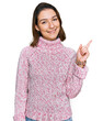 © Krakenimages.com - Young caucasian girl wearing wool winter sweater with a big smile on face, pointing with hand finger to the side looking at the camera.