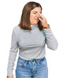 © Krakenimages.com - Young beautiful woman wearing casual turtleneck sweater smelling something stinky and disgusting, intolerable smell, holding breath with fingers on nose. bad smell