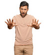 © Krakenimages.com - Handsome hispanic man wearing casual clothes doing stop gesture with hands palms, angry and frustration expression