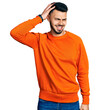 © Krakenimages.com - Young hispanic man with beard wearing casual orange sweater confuse and wonder about question. uncertain with doubt, thinking with hand on head. pensive concept.