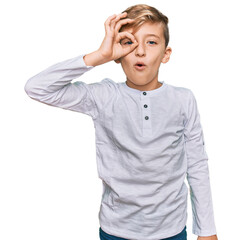 Wall Mural - Little caucasian boy kid wearing casual clothes doing ok gesture shocked with surprised face, eye looking through fingers. unbelieving expression.