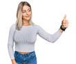 © Krakenimages.com - Beautiful blonde woman wearing casual clothes looking proud, smiling doing thumbs up gesture to the side