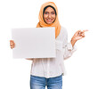 © Krakenimages.com - Young brunette arab woman wearing traditional islamic hijab holding banner smiling happy pointing with hand and finger to the side