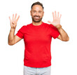 © Krakenimages.com - Handsome middle age man wearing casual red tshirt showing and pointing up with fingers number nine while smiling confident and happy.