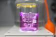 © Marco Reggi/Stocksy - Purple liquid swirling in a beaker during a lab experiment