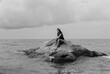 © Polina Kovalova/Stocksy - A young woman sitting on a rock in the sea
